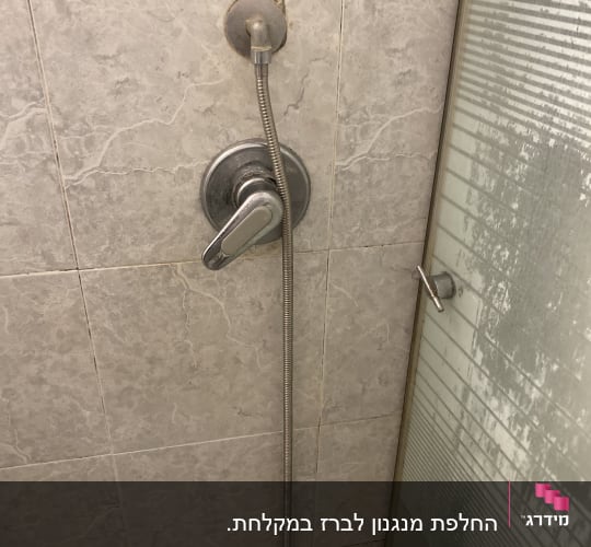ברז מקלחת עם צינור מתכת על קיר אריחים